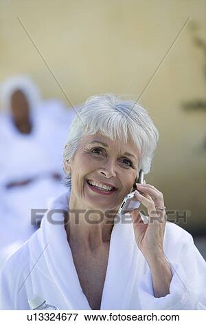 Stock Photo - Portrait of senior woman in bathrobe using mobile phone. Fotosearch