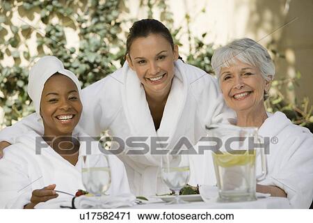 Stock Image - Portrait of three women in bathrobes at health spa. Fotosearch