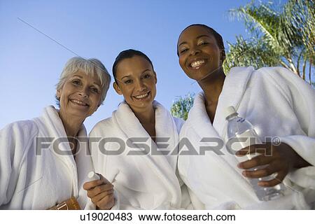 Stock Image - Portrait of three women in bathrobes at health spa. Fotosearch