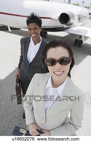 Portrait of two mid-adult businesswomen in front of private plane, elevated view. View Large Photo Image Stock Photograph - Portrait of two mid-adult businesswomen in front of private plane, elevated view.. Fotosearch