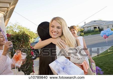 Stock Image - Pregnant Asian Woman embracing Friend at a Baby Shower. Fotosearch
