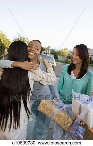 Stock Image - Pregnant Asian Woman embracing Friend at a Baby Shower. Fotosearch