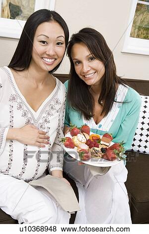 Stock Photo - Pregnant Asian Woman with Friend at a Baby Shower. Fotosearch