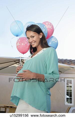 Stock Photograph - Pregnant Woman holding balloons, outside. Fotosearch