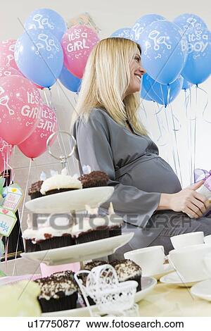 Stock Photo - Pregnant Woman sitting down at a Baby Shower. Fotosearch