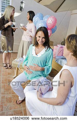 Stock Photograph - Pregnant Woman sitting on bench at a Baby Shower. Fotosearch