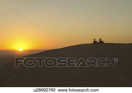 Stock Image - Quad bikes in desert at sunset, silhouette. Fotosearch