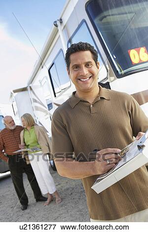 Stock Photo - Salesperson with clipboard, customers in background, portrait. Fotosearch
