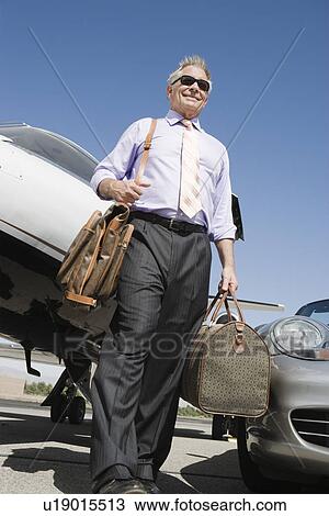 Senior businessman in front of car and airplane, low angle view. View Large Photo Image Stock Image - Senior businessman in front of car and airplane, low angle view.. Fotosearch