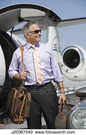 Stock Image - Senior businessman in front of private jet.. Fotosearch
