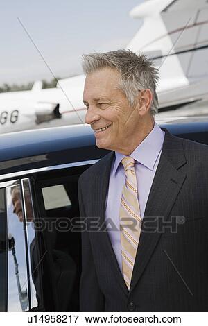 Stock Photo - Senior businessman in front of limousine and private jet.. Fotosearch