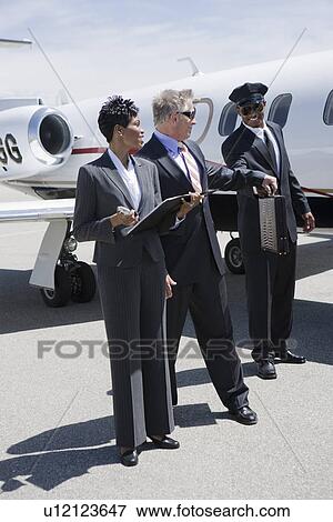 Senior businessman, mid-adult businesswoman and airline pilot in front of private jet. View Large Photo Image Stock Photo - Senior businessman, mid-adult businesswoman and airline pilot in front of private jet.. Fotosearch