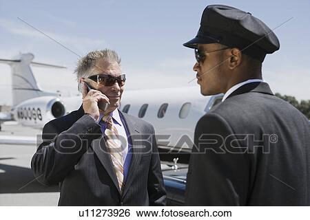 Senior businessman standing outside private jet and talking on phone, Chauffeur assisting. View Large Photo Image Stock Photograph - Senior businessman standing outside private jet and talking on phone, Chauffeur assisting.. Fotosearch