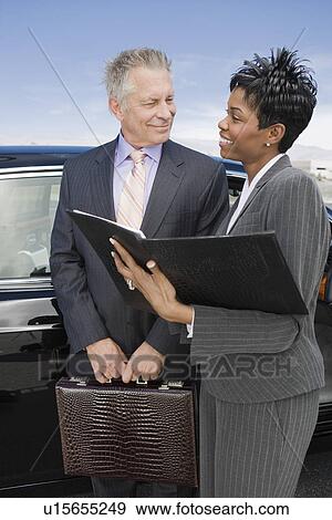 Senior businessman with mid-adult businesswoman standing in front of car. View Large Photo Image Stock Photo - Senior businessman with mid-adult businesswoman standing in front of car.. Fotosearch