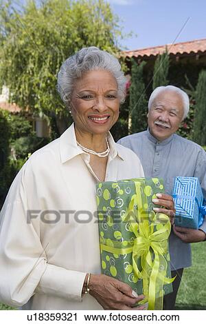 Senior man and woman holding birthday presents, smiling View Large Photo Image Stock Image - Senior man and woman holding birthday presents, smiling. Fotosearch