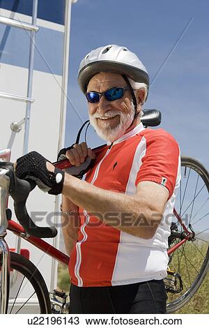 Stock Image - Senior man carrying bike. Fotosearch