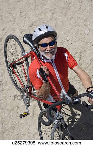 Stock Photography - Senior man carrying bike. Fotosearch