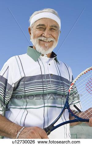 Stock Photograph - Senior man holding tennis racket, portrait. Fotosearch