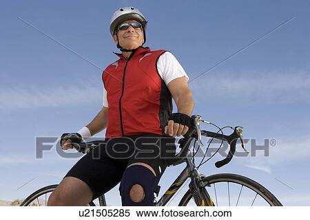 Stock Photography - Senior man leaning on bike. Fotosearch