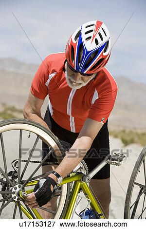 Stock Photo - Senior man repairing bike. Fotosearch