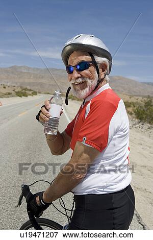 Senior man with bike drinking water View Large Photo Image Stock Photo - Senior man with bike drinking water. Fotosearch