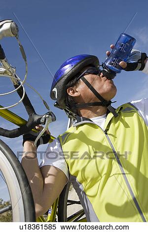 Stock Photography - Senior man with bike drinking water. Fotosearch