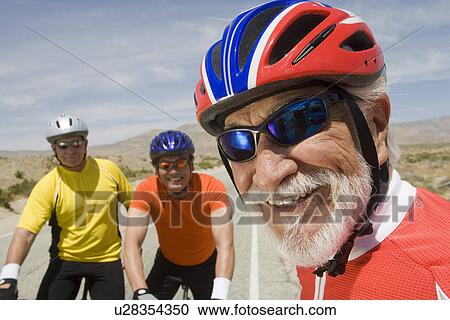 Stock Image - Senior men wearing cycling helmets. Fotosearch