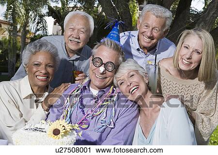 Stock Image - Senior people celebrating birthday in garden, smiling. Fotosearch