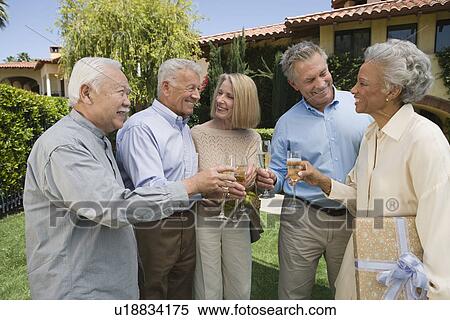 Stock Photography - Senior people raising toast in garden while birthday party. Fotosearch
