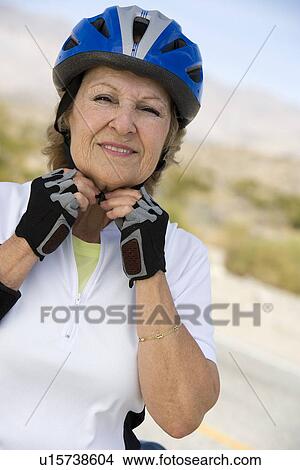Picture - Senior woman adjusting cycling helmet. Fotosearch