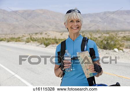 Stock Photo - Senior woman holding map and water bottle. Fotosearch