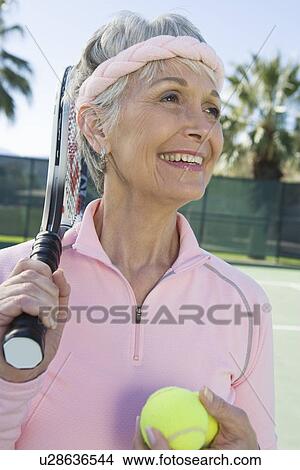 Picture - Senior woman holding tennis racket and balls. Fotosearch