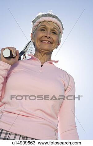 Stock Image - Senior woman holding tennis racket, portrait. Fotosearch