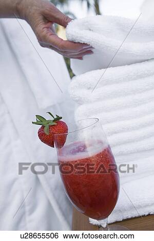 Stock Photograph - Senior woman holding towel near strawberry cocktail, close-up. Fotosearch