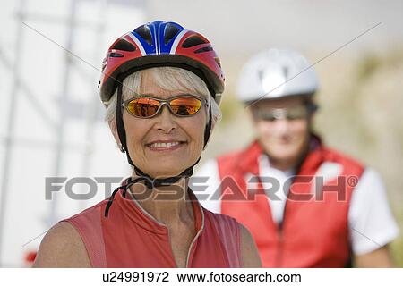 Stock Image - Senior woman wearing cycling helmet. Fotosearch