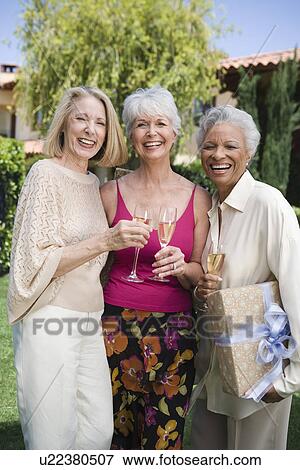 Senior woman with two friends, smiling and holding champagne View Large Photo Image Stock Photo - Senior woman with two friends, smiling and holding champagne. Fotosearch