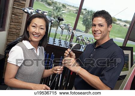 Smiling Clerk assisting mid-adult woman shopping for golf clubs in Golf Shop View Large Photo Image Stock Photography - Smiling Clerk assisting mid-adult woman shopping for golf clubs in Golf Shop. Fotosearch
