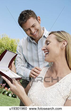 Stock Image - Smiling Wife Receiving a Pearl Necklace from husband outside. Fotosearch