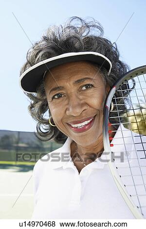 Stock Photo - Smiling Woman on the Tennis Court holding tennis racket. Fotosearch