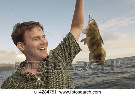 Stock Image - Sport fisherman with fish at sea. Fotosearch