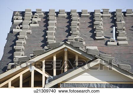 Stock Image - Stacks of tiles on house roof. Fotosearch