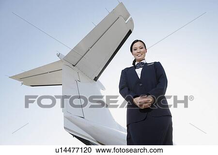 Stewardess in uniform, standing below wing of private jet, low angle view View Large Photo Image Stock Image - Stewardess in uniform, standing below wing of private jet, low angle view. Fotosearch