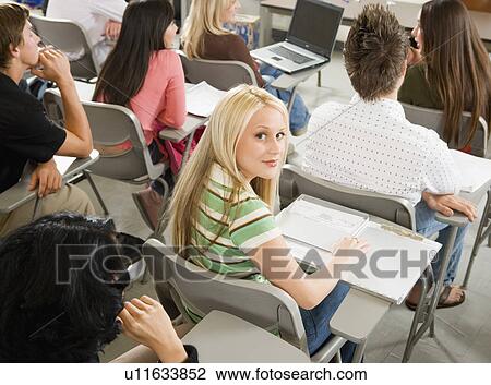 Stock Image - Student sitting at desk during class, (portrait). Fotosearch