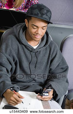 Stock Photo - Student using mobile phone during class. Fotosearch