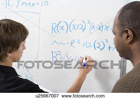 Stock Photo - Student writing maths equations on whiteboard with tutor. Fotosearch