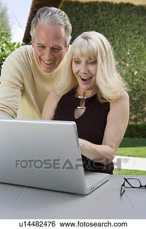 Stock Photograph - Surprised couple using laptop in back yard. Fotosearch