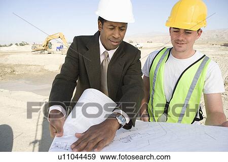 Stock Photo - Surveyor and construction worker studying blueprint. Fotosearch