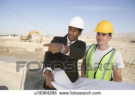 Stock Photography - Surveyor and construction worker holding blueprint. Fotosearch