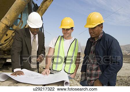 Stock Image - Surveyor and construction workers on site. Fotosearch
