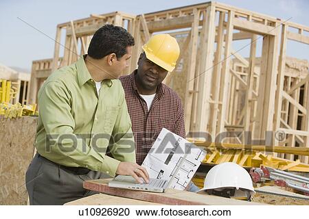 Stock Image - Surveyors working on construction site. Fotosearch